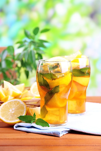 Iced tea with lemon and mint on wooden table outdoors