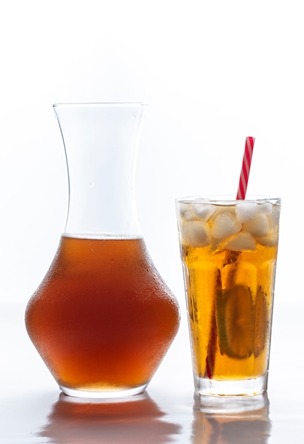 Iced tea with straw, ice cubes and sliced lemon and a glass bottle