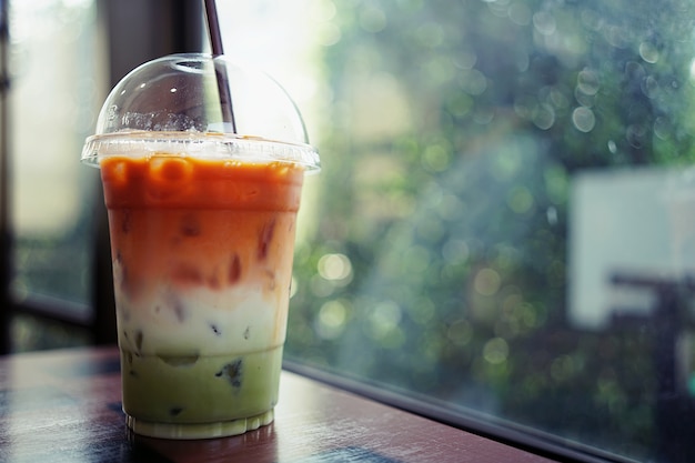 Ледяной трехслойный напиток состоит из тайского чая, молока и зеленого чая в пластиковой чашке