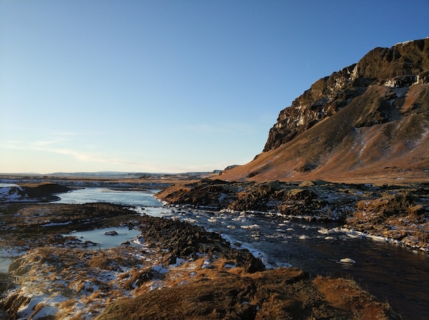 冬のアイスランドの息を呑むような山の風景、滝のある川。自然の絵の具。