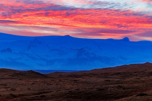見事な夕日を持つアイスランドの寒い高地、夜の写真のコンセプト。壮大な北欧の山脈の上に沈む夕日による、空のようなバラ色の綿菓子の息を呑むような景色。