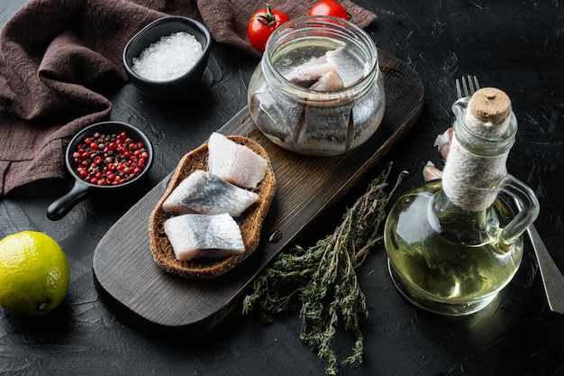 Icelandic herring set, on wooden cutting board, on black background with herbs and ingredients