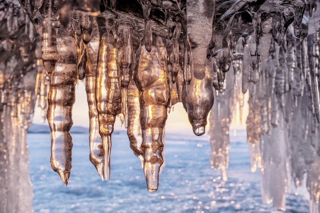 Icicles in cave on Baikal lake at sunset