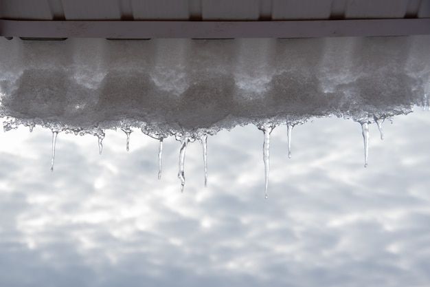 icicles hanging from the roof of the house against a blue sky