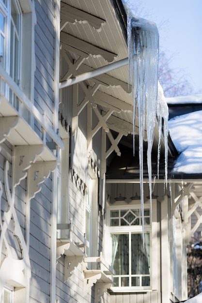 Icicles hanging from the roof of a wooden building in winter in sunny weather
