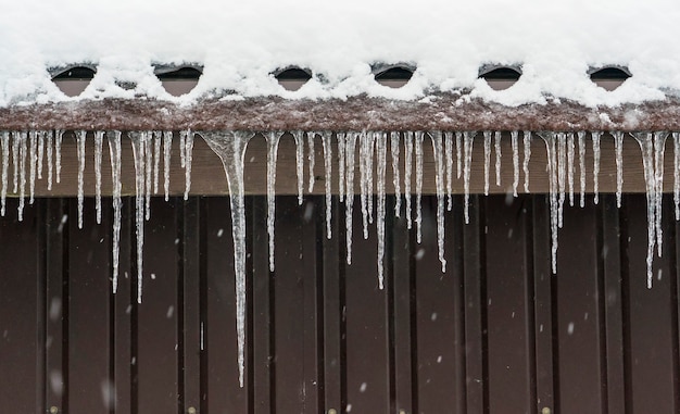 Photo icicles of ice hang from the roof of the house.