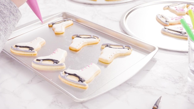 Icing figure skate shaped sugar cookies with royal icing.