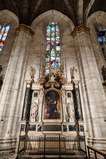 Icoon op een voetstuk omringd door engelen bij een glas-in-loodraam in de duomo milaan italië