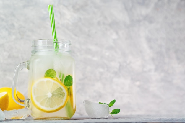 Icy refreshing summer homemade lemonade with lemon and mint on a gray table copy space
