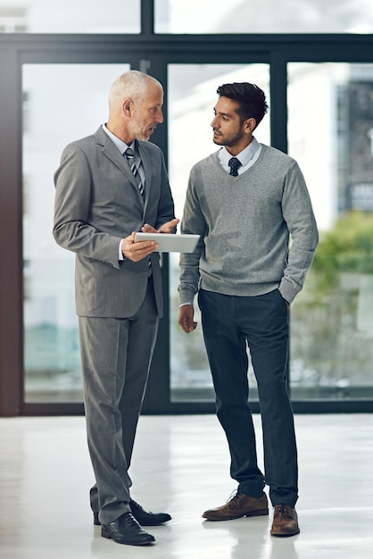 Id like your thoughts on this Full length shot of two businessmen looking at a digital tablet in their office