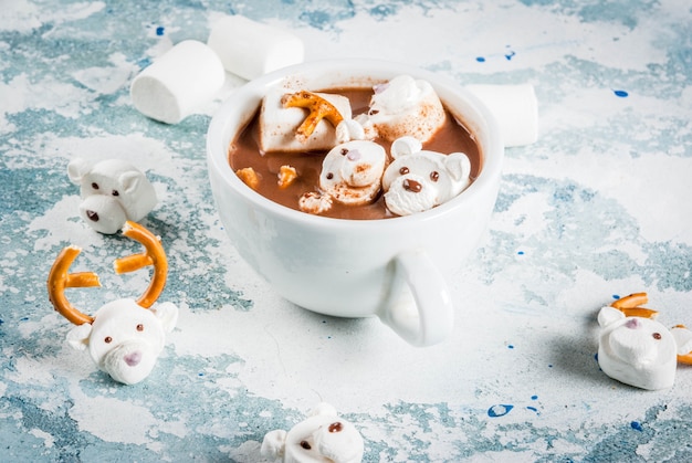 Idea for a children's Christmas snack, hot chocolate with teddy bears and deer marshmallow. On a light surface, copy space