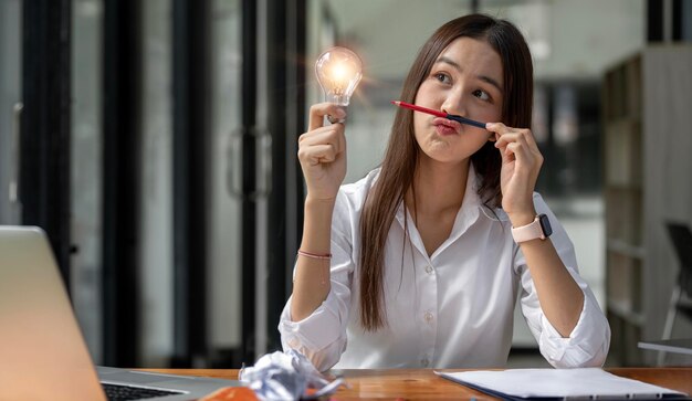 Photo idea concept young asian girl looking lightbulb in her hand with thoughtful face