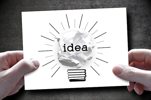 Idea creativity concept human hands holding piece of paper with paperball light bulb