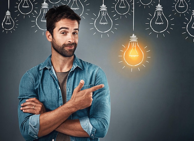 an idea is the seed of creation studio portrait of a handsome young man pointing towards an illustration of a lit light bulb against a grey background