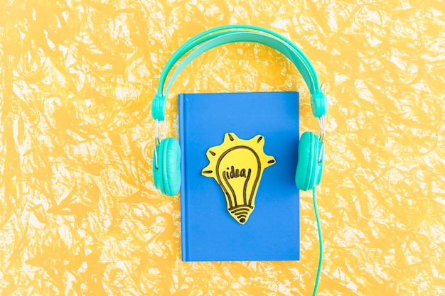 Photo idea light bulb on blue cover notebook with headphone on yellow backdrop