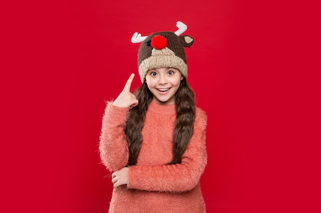 Idea of teen child in winter fashion hat isolated on red teen child wear sweater