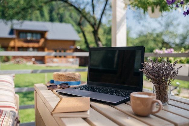 Ideale plek om in de zomer te werken. laptop, kladblok en kopje koffie staan op een houten tafel. bedrijfsconcept foto