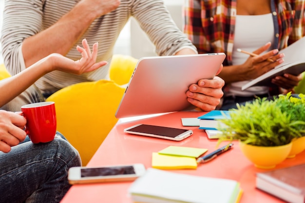 Ideas are born here. Close-up of three young people working together while sitting at their working place