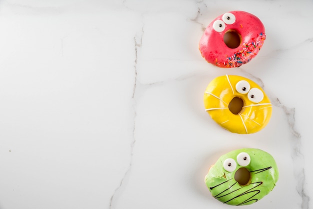 Ideas for children treats on Halloween. Colorful  donuts in the form of monsters 