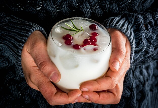 Ideas for drinks for Xmas and thanksgiving. Female hands with white christmas margarita punch with cranberries and rosemary, cozy, close view,