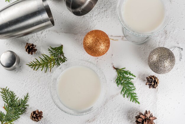 クリスマスの飲み物のアイデアとレシピ。ホワイトチョコレートスノーフレークマティーニカクテル、クリスマス装飾、トップビューで白い大理石のテーブルの上