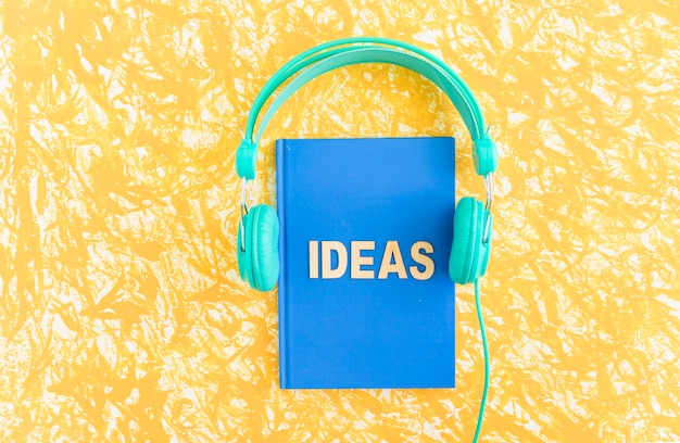 Photo ideas text on blue cover notebook with headphone on yellow backdrop