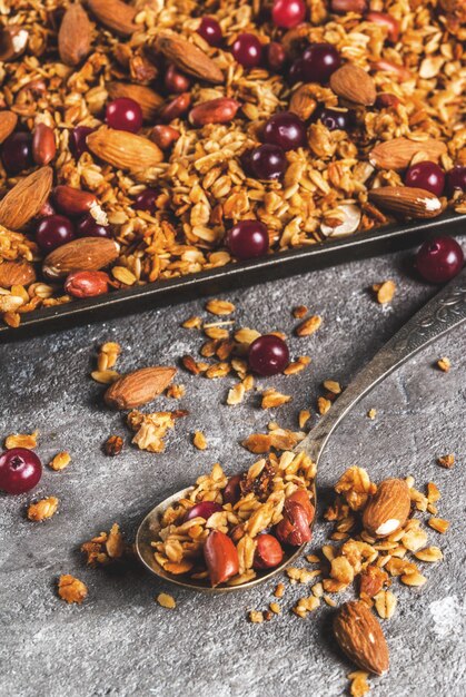 Ideas for a winter autumn breakfast Thanksgiving Christmas Homemade fresh cooked honey granola with nuts (almonds peanuts hazelnuts) and cranberries On gray concrete table