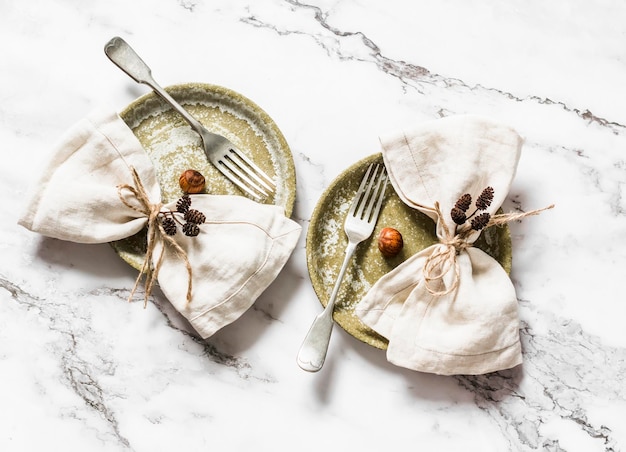 Idee van serveren is vintage keramische borden en linnen servetten versierd met kegels en noten op een lichtmarmeren achtergrond bovenaanzicht