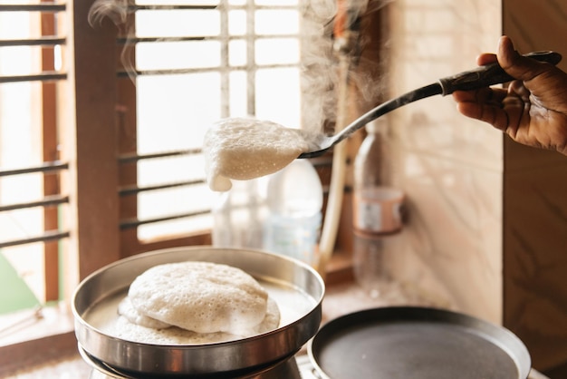 Foto idli o idly torta di riso salata dell'india cibo per la colazione a sud donna che cucina a casa cibo caldo