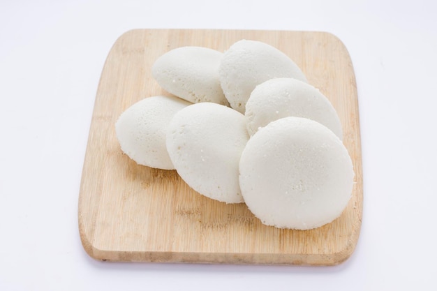 Idly or Idli south indian main breakfast item which is beautifully arranged in a wooden base with white background