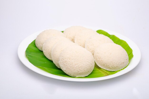 Idly  south Indian main breakfast item which is arranged in a white plate lined with banana leaf