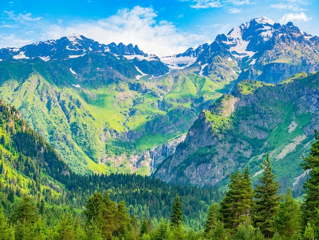 Idyllic landscape with blue sky, green forest and snowcapped mountain top. Svanetia region, Georgia