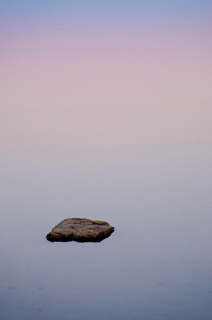 Idyllic shot of rock in lake under foggy weather