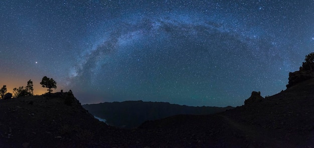 Foto scatto idilliaco del campo stellato sopra la montagna a silhouette