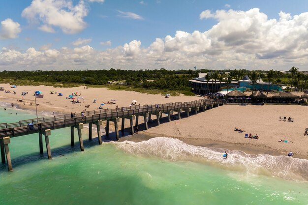 Photo idyllic summer day over sandy beach at venice fishing pier in florida summer seascape with surf waves crashing on sea shore