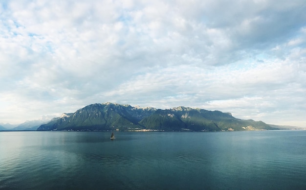 Idyllische opname van een meer en een bergketen tegen een bewolkte lucht