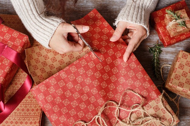 Iemand die ambachtelijk papier snijdt en cadeautjes inpakt op houten tafelblad