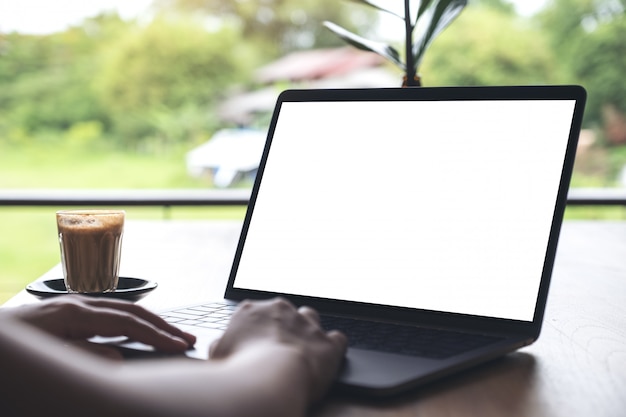 Iemand gebruikt laptop, met een koffiekopje op houten tafel