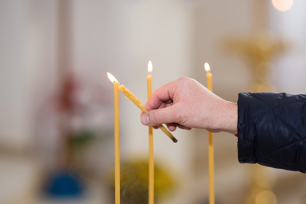 Iemands hand steekt een kaars aan in een kerk