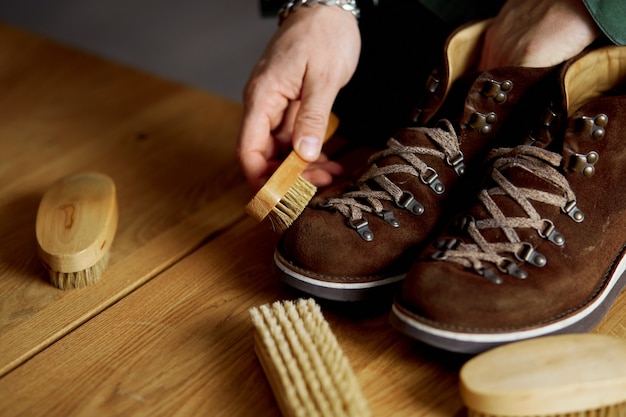 Iemands hand suède schoenen schoonmaken met een borstel op houten vloer