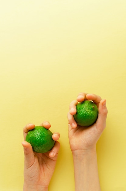 Iemands handen houden twee groene limoenen vast