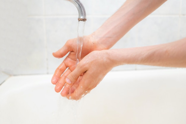 Iemands handen wassen met stromend water in de badkamer