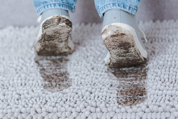 Iemands schoenen zijn bedekt met modder op een tapijt