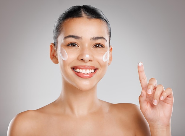 If my skin loves it I love it too Studio shot of an attractive young woman applying moisturiser to her face against a grey background