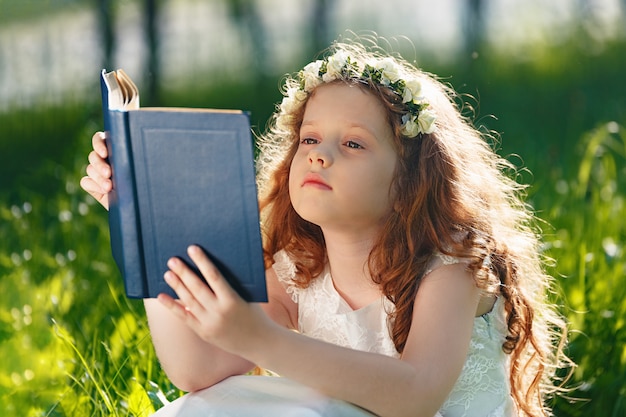 Iittle girl reading a book in the park