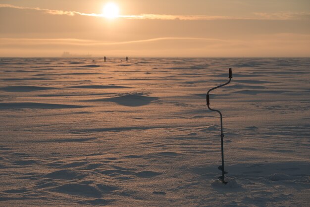 Ijs boor. Bevroren zee op de achtergrond. Landschap rond het thema wintervissen.