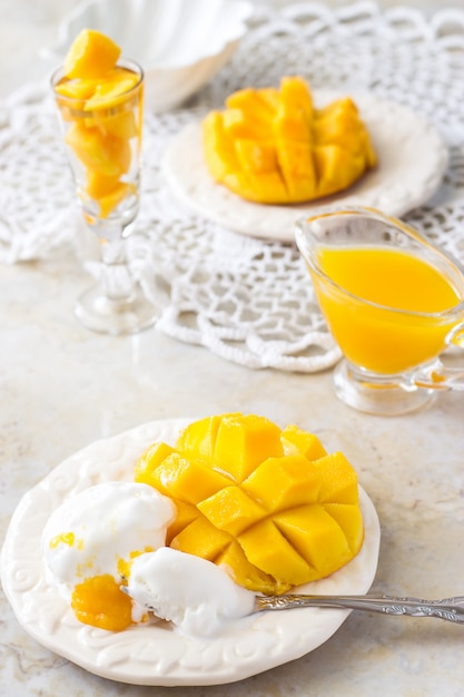 IJs en Mango fruit halve blokjes en mango sap puree op wit Concrete achtergrond.