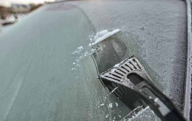 IJs uit de autoruit schrapen Concept van voertuigvoorbereiding voor een rit wanneer de buitentemperatuur onder nul is