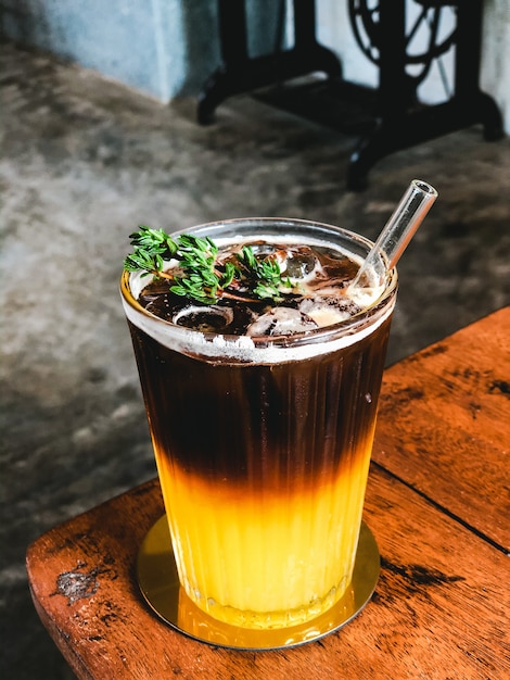 IJs vers sinaasappelsap gegarneerd met espresso op houten tafel in moderne café.