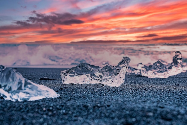 Foto ijsbergbrok op zwart zand bij diamantstrand tegen dramatische hemel tijdens zonsondergang